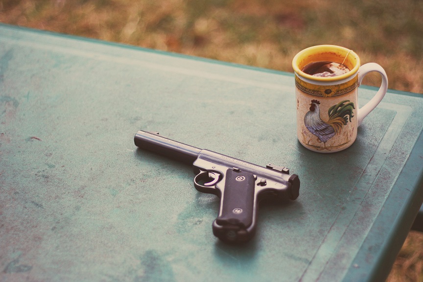 Pistola sobre uma mesa verde, ao lado de uma xícara de chá