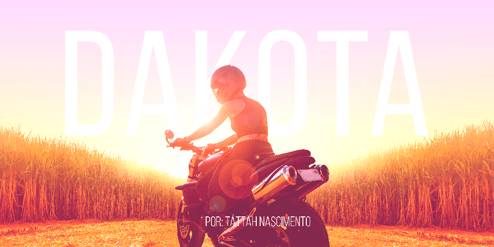 Mulher sobre uma moto em uma estrada cortada por um canavial.